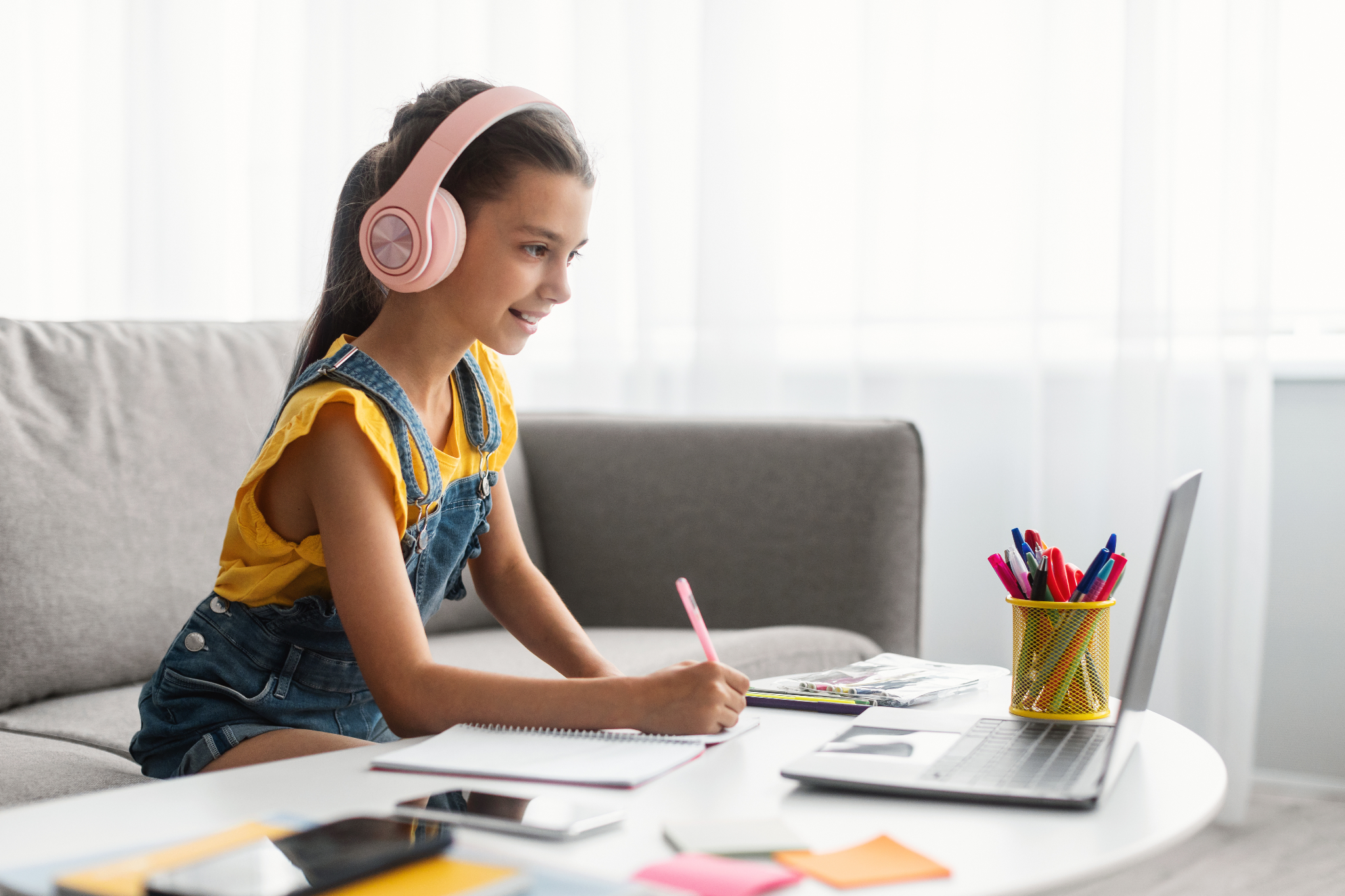 Student sitting on a couch with headphones on working